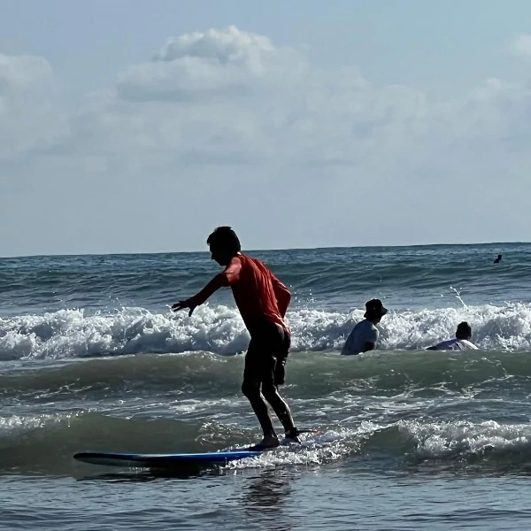 Niño montando tabla de surf mientras recibe clase de surf