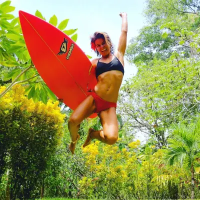 woman jumping with a surfboard