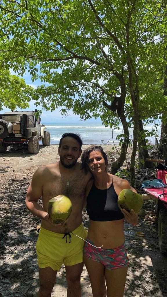 a man and at woman drinking coconut water near the beach on green season