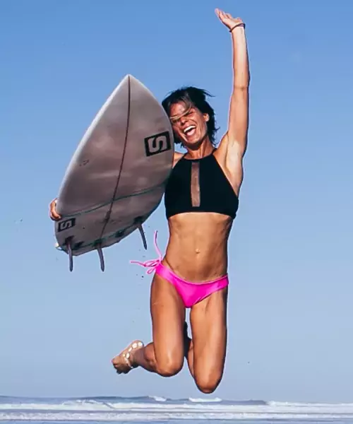 woman on beach with surfboard