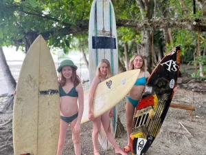 three girls pose with surfboards on the beach