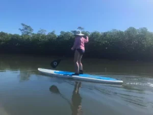 woman standing board paddling on estuary