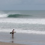 A lonely surfer waits the right moment to get in the water after a mild rain in Santa Teresa Beach. A lonely surfer in a cloudy day